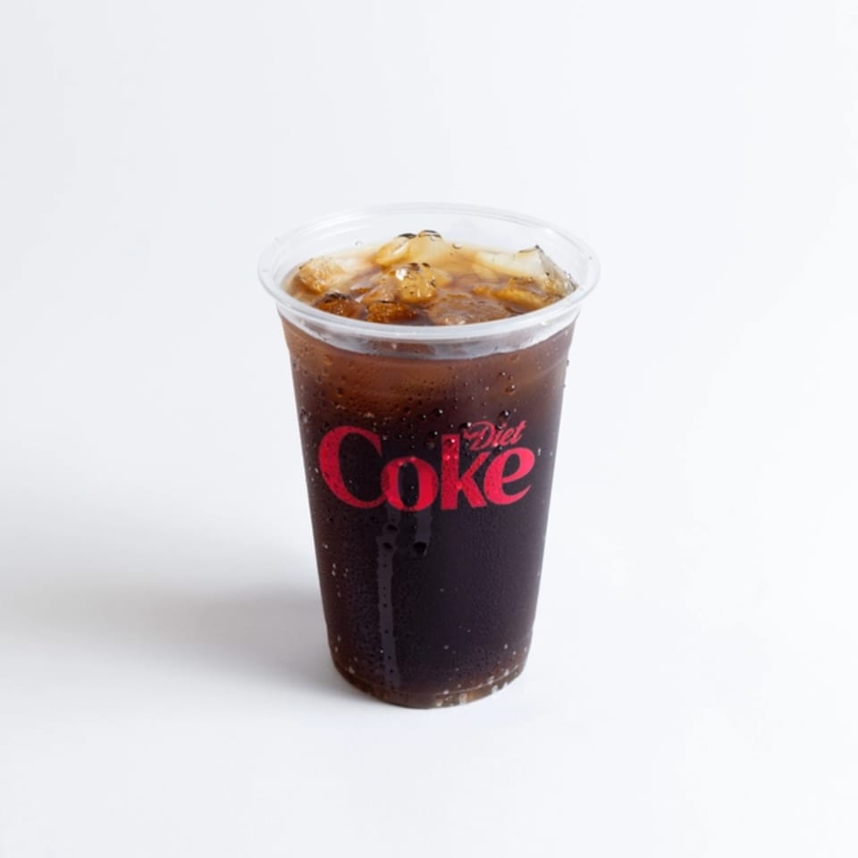 A plastic cup of Diet Coke with ice, condensation on the side, against a white background.
